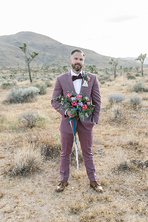  groom in a rose pink suit with a burgundy bow tie