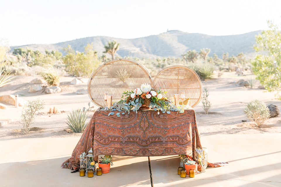  bohemian sweetheart table with wicker chairs and bohemian florals