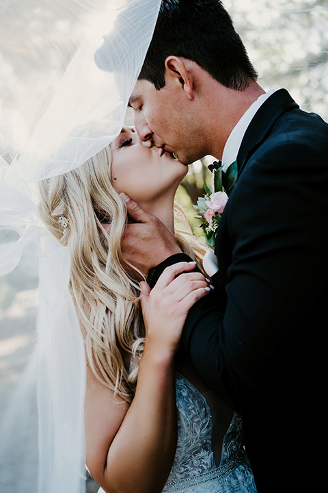 bride in a white ballgown with a strapless neckline and a long veil and the groom in a notch lapel tuxedo and black bow tie dancing 