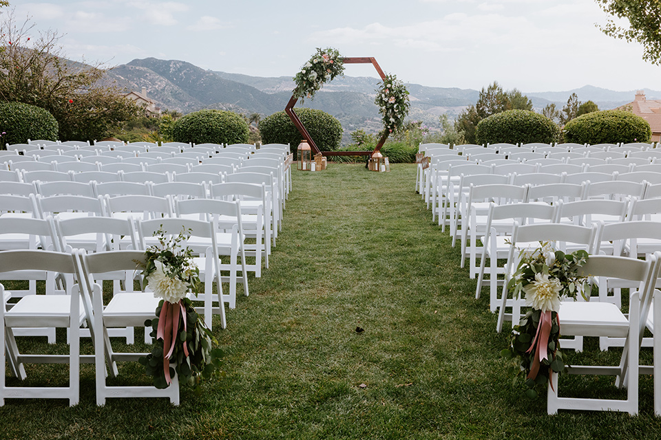  white chairs and floral archway overlooking the hills