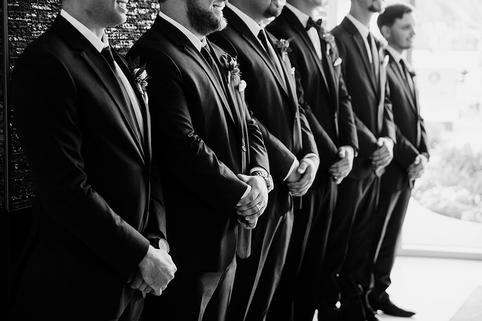  groom and groomsmen in black tuxedos with black bow ties