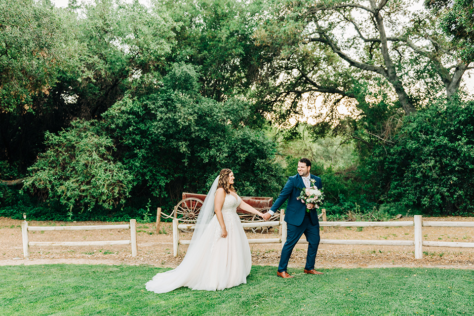  bride in a white ball gown with train and the groom in a dark blue suit in bow tie 