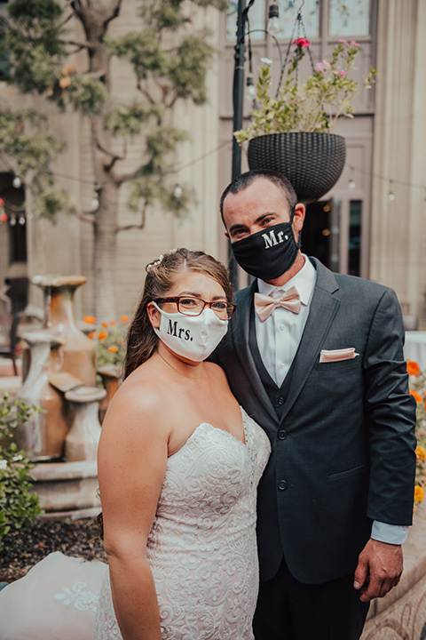  bride in a formfitting white lace gown with a long train and the groom in a dark blue suit