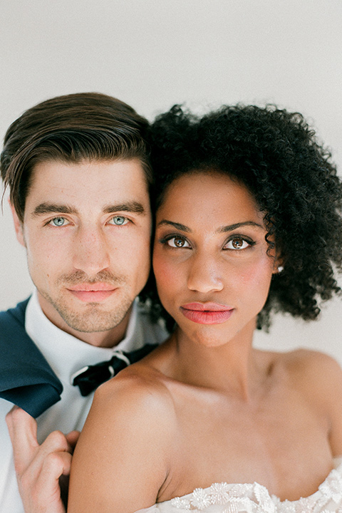  bride in a tulle ballgown with an off the shoulder detail and full billowed sleeves and the groom in a slate blue suit with a matching bow tie