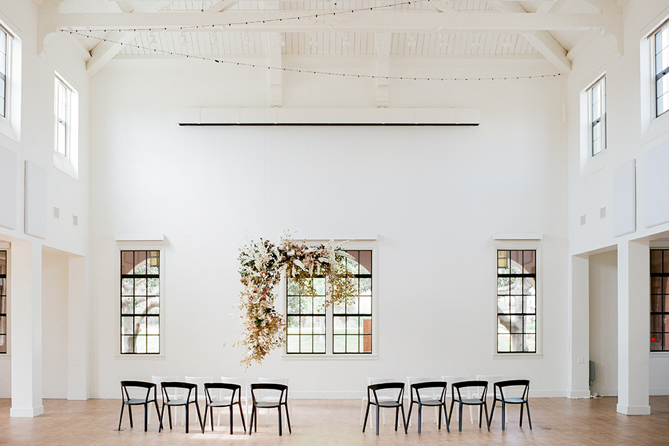  white ceremony décor with black chairs and soft floral arrangements