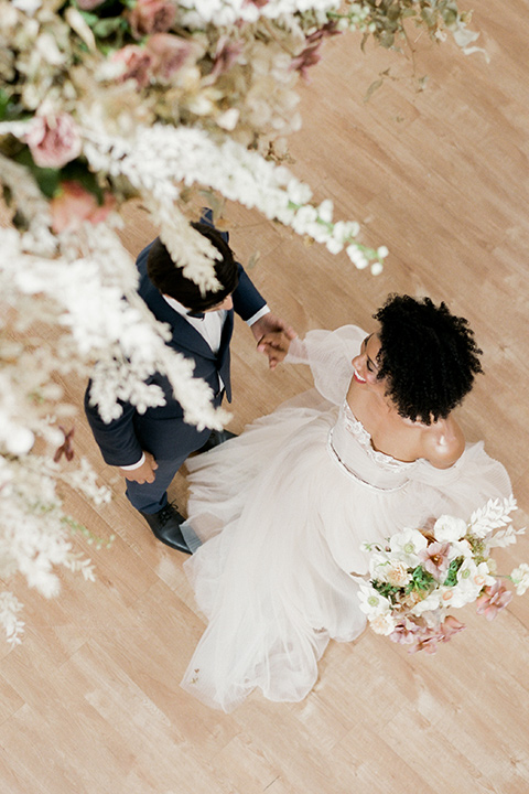  bride in a tulle ballgown with an off the shoulder detail and full billowed sleeves and the groom in a slate blue suit and matching bow tie