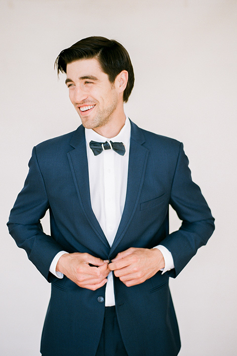  bride in a tulle ballgown with an off the shoulder detail and full billowed sleeves and the groom in a slate blue suit with a matching bow tie dancing