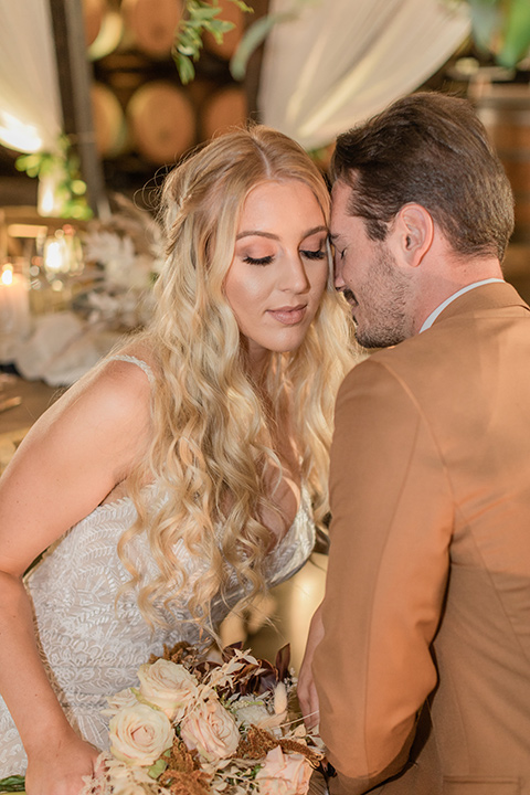 bride in a lace bohemian gown and the groom in a caramel brown suit with a chocolate brown long tie and fun pocket square at the reception 