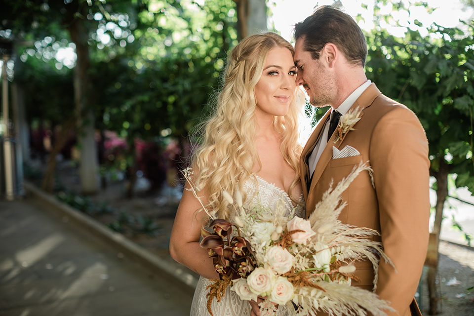 bride in a lace bohemian gown and the groom in a caramel brown suit with a chocolate brown long tie and fun pocket square in the winery