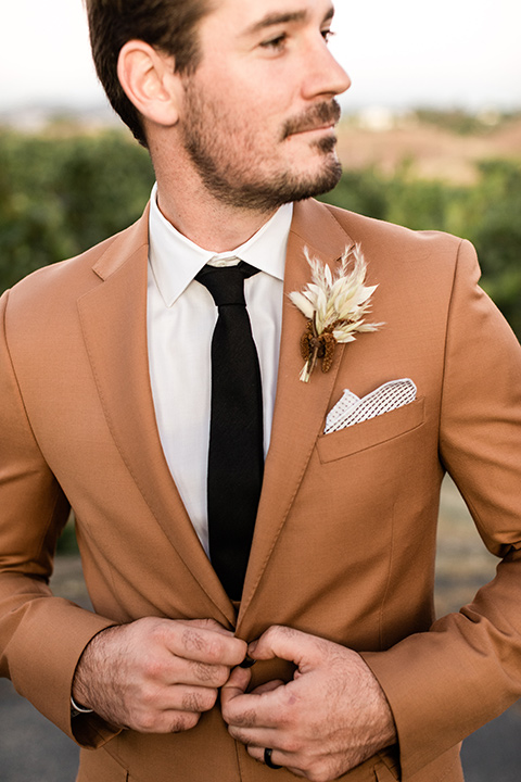   groom in a caramel brown suit with a chocolate brown long tie and fun pocket square 