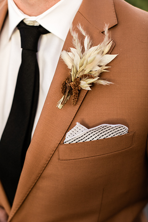  groom in a caramel brown suit with a chocolate brown long tie and fun pocket square 