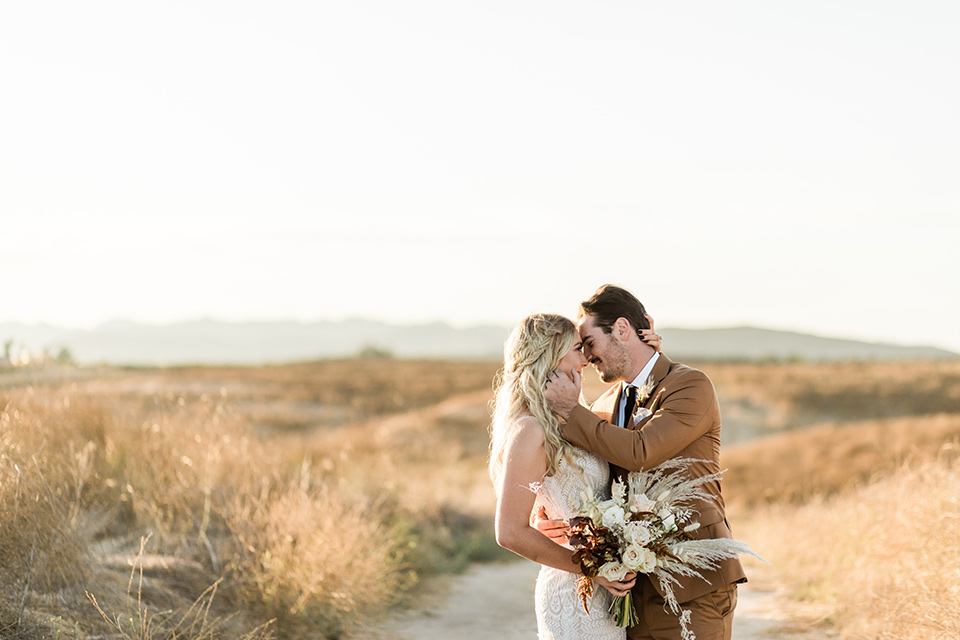 bride in a lace bohemian gown and the groom in a caramel brown suit with a chocolate brown long tie and fun pocket square 