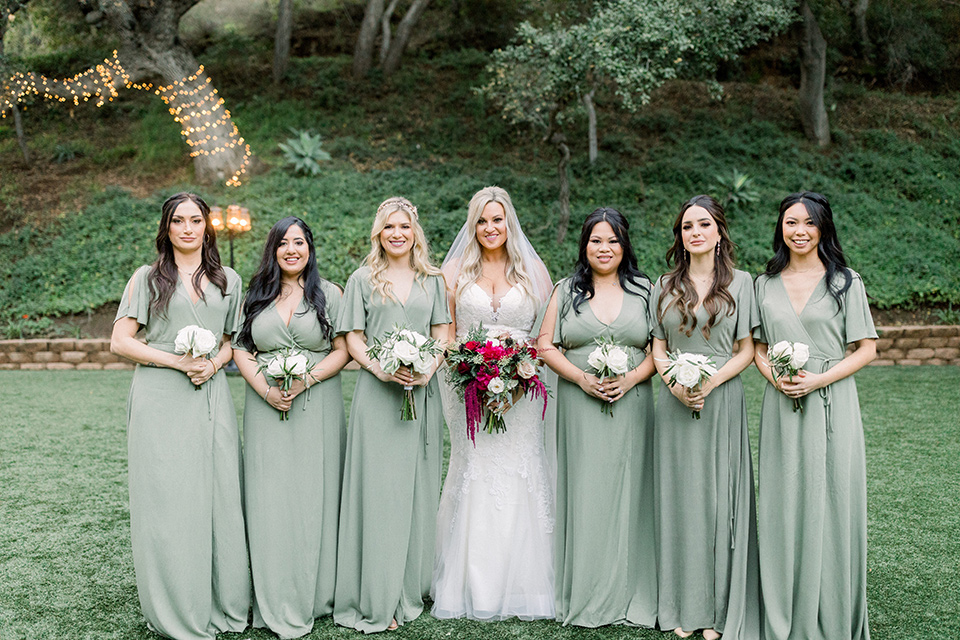  bride in a mermaid style lace white gown and the bridesmaids in sage green dresses