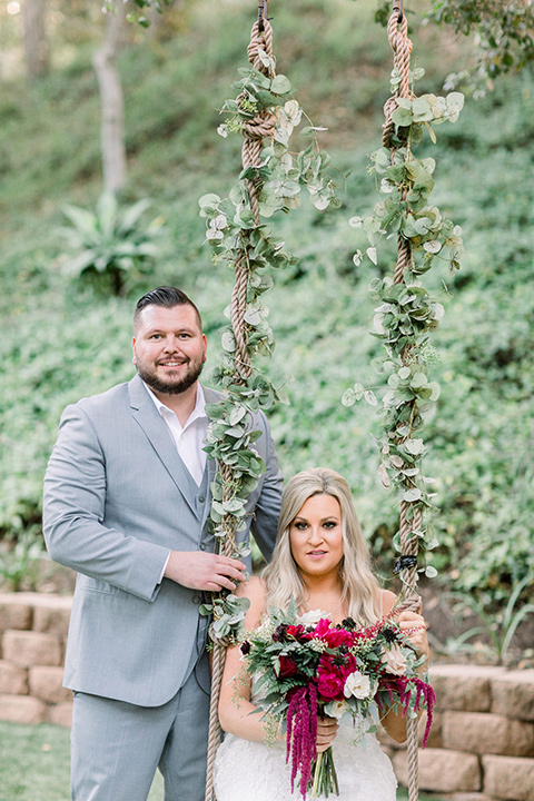  bride in a white lace mermaid style gown and a strapless neckline and groom in a light grey suit at the ceremony