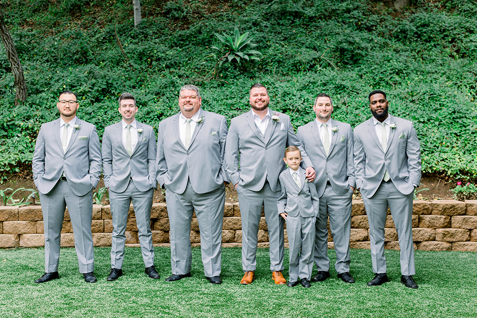  groom in a light grey suit with a light brown shoes and the groomsmen in light grey suits and bow ties