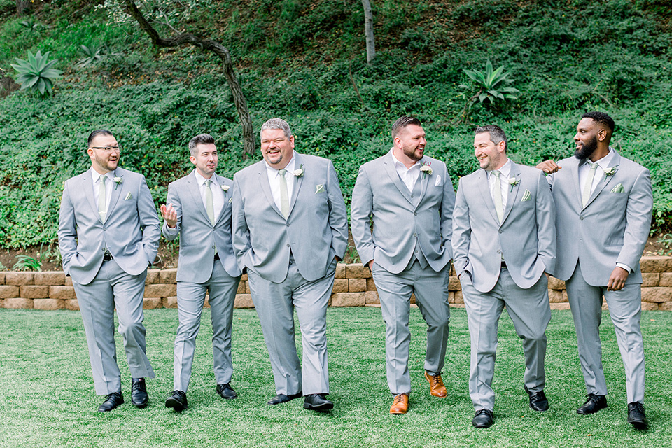  groom in a light grey suit with a light brown shoes and the groomsmen in light grey suits and bow ties