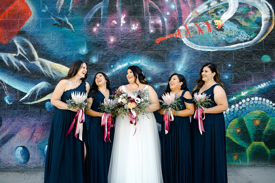  bride in a tulle ballgown with cap sleeves and the bridesmaids in black long gowns