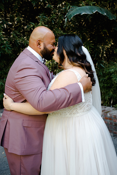  bride in a tulle ballgown with cap sleeves groom in a rose suit with a floral bow tie