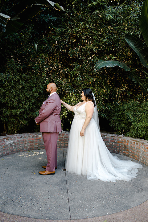  bride in a tulle ballgown with cap sleeves groom in a rose suit with a floral bow tie