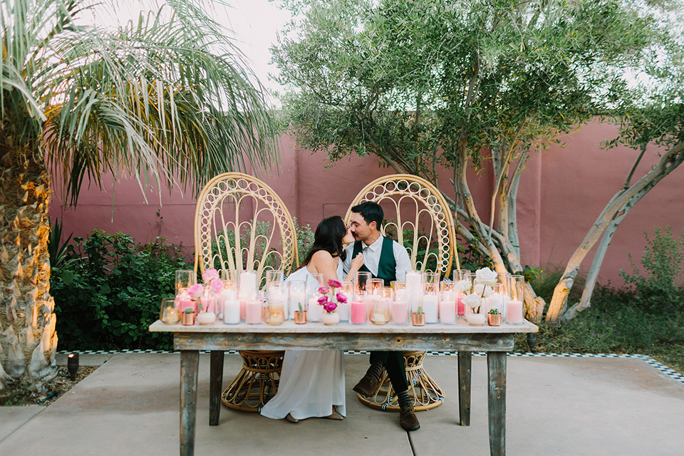  wooden table with boho wicker chairs and pink and green décor on the table 