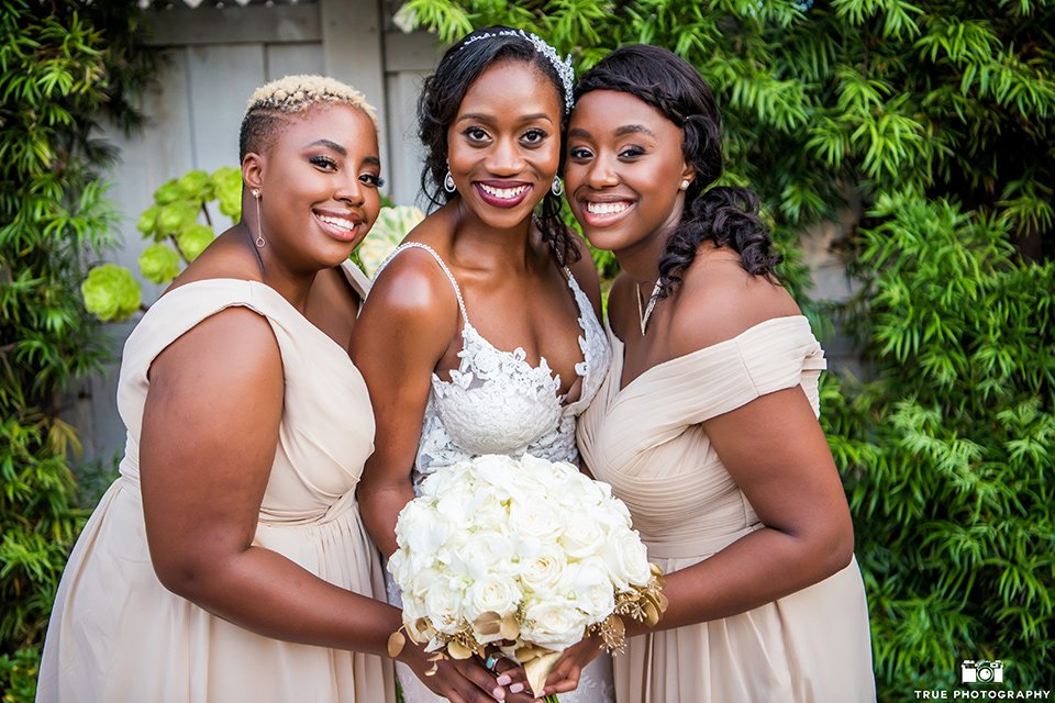  bride in a white formfitting gown with a plunging neckline and the bridesmaids in gold long gowns