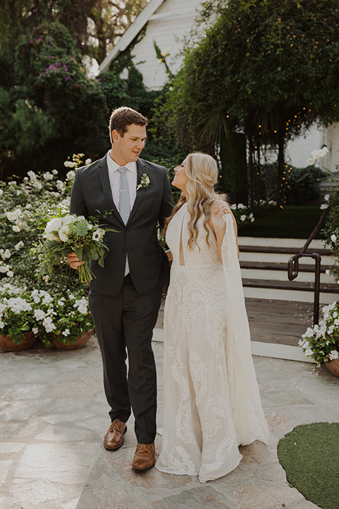  the bride in a flowing white gown with a high lace neckline and a long cathedral veil, the groom in an asphalt grey suit by Michael Kors with a light blue patterned long tie 