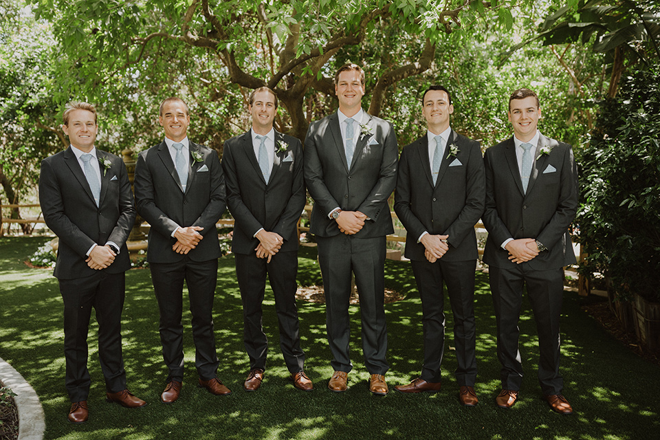  =” the groom in an asphalt grey suit by Michael Kors with a light blue patterned long tie and the groomsmen in dark grey suits with floral long ties at the ceremony