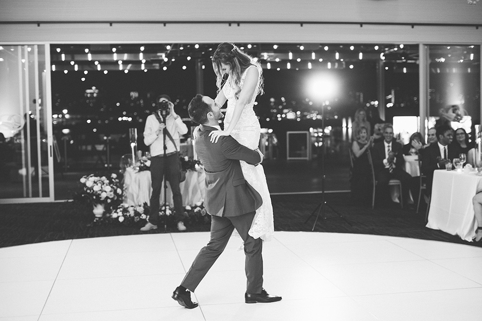  bride in an ivory lace gown with a modern geometric pattern and a v neckline, the groom wore a cobalt blue suit with a black bowtie during their first dance 