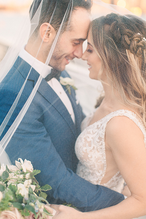  bride in an ivory lace gown with a modern geometric pattern and a v neckline, the groom wore a cobalt blue suit with a black bowtie under veil