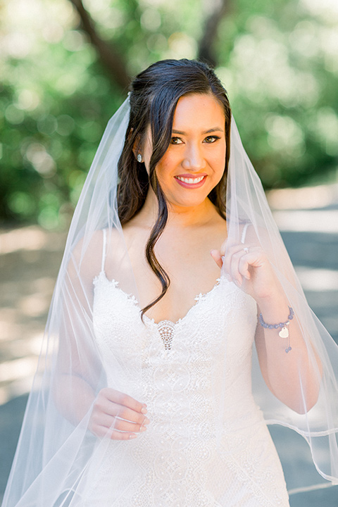  bride in a white lace gown with thin straps and veil