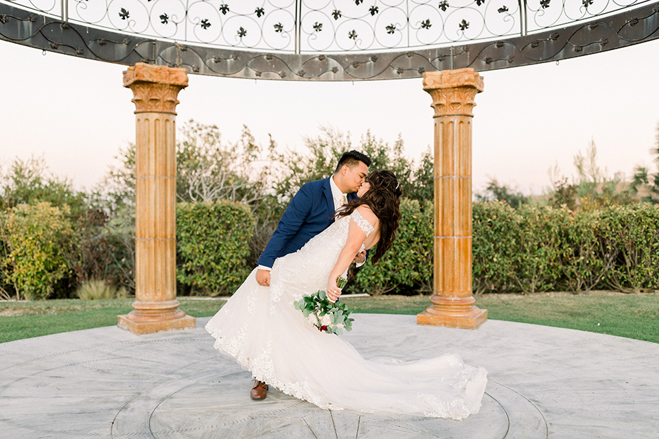  bride in a Spanish style lace gown with off the shoulder detailing, the groom in a cobalt suit with a pink long tie dipping bride