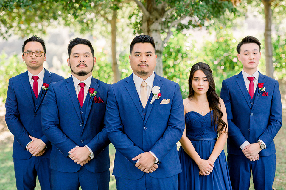  the groomsmen in cobalt suits with red long ties and a groomswoman in a cobalt dress