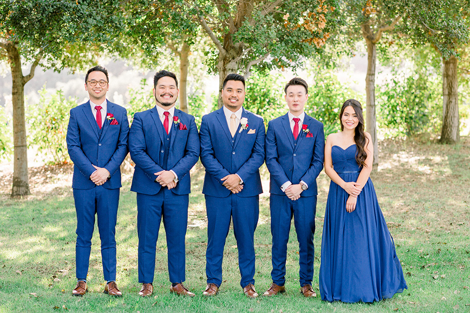  the groomsmen in cobalt suits with red long ties and a groomswoman in a cobalt dress