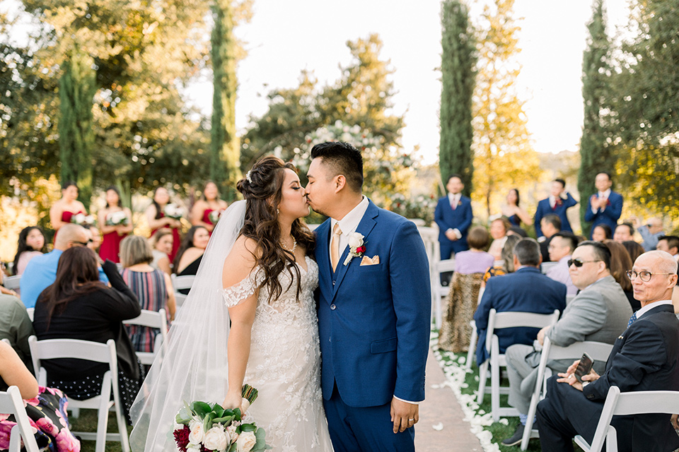  bride and groom kissing at the end of the aisle