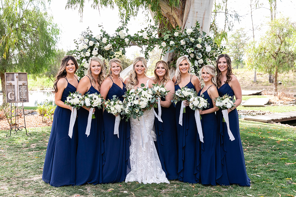  bride in a white lace gown and the bridesmaids in navy long gowns