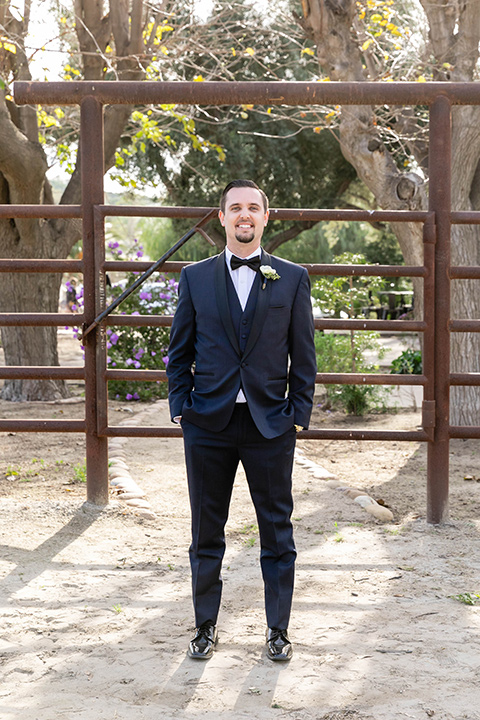  groom in a navy shawl lapel tuxedo with a black bow tie