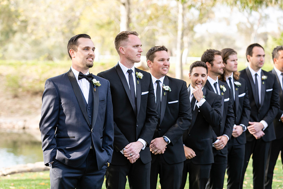  groom in a navy shawl lapel tuxedo and groomsmen in black tuxedos