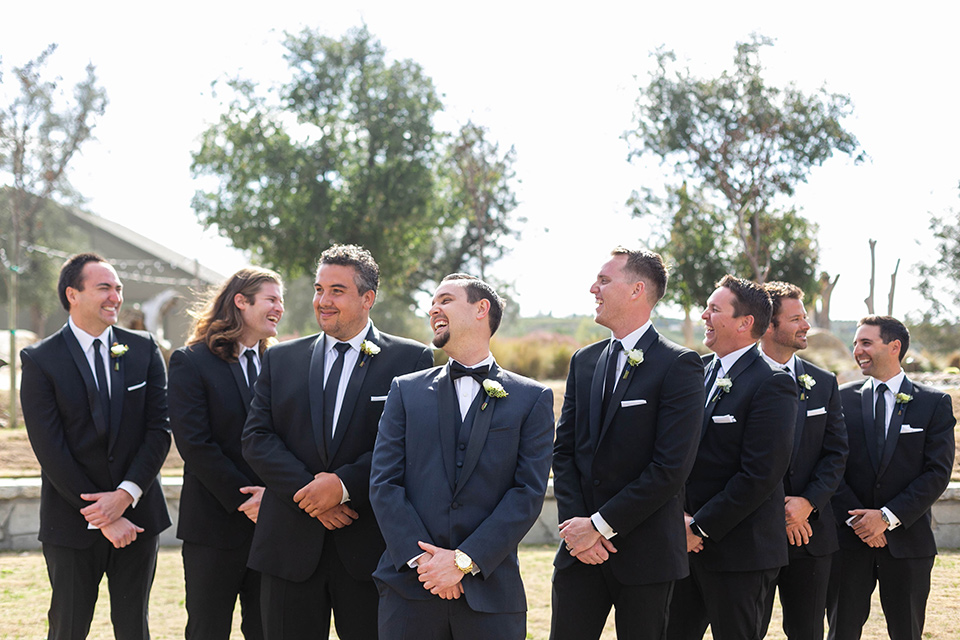  groom in a navy shawl lapel tuxedo and groomsmen in black tuxedos