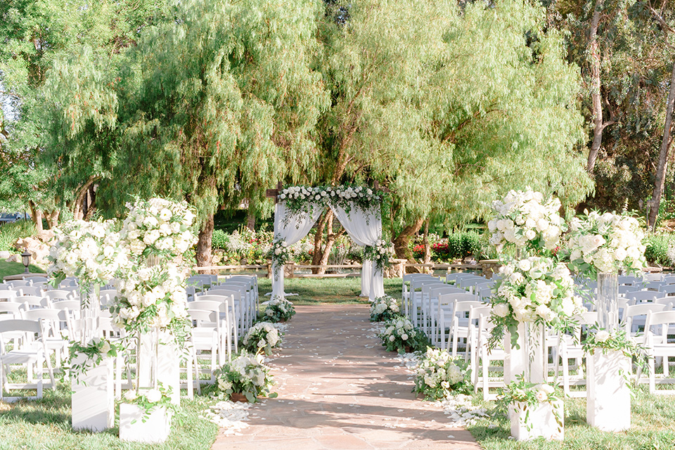  bride in a white lace gown with a long train and veil, groom in a cobalt blue suit with a blue floral long tie at the ceremony 