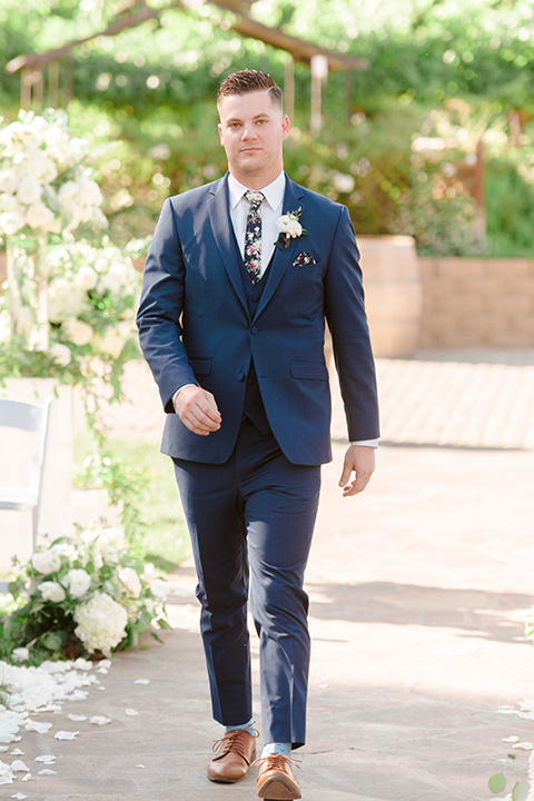  groom in a cobalt blue suit with a blue floral long tie walking down the aisle