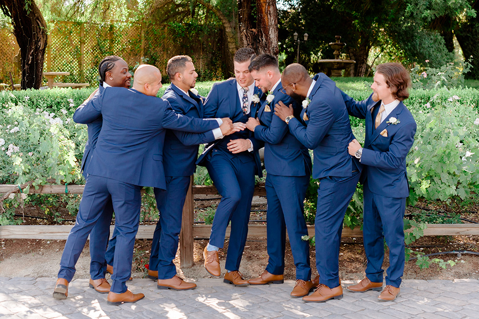  groom in a cobalt blue suit with a blue floral long tie and groomsmen in cobalt blue suit with blue floral bow ties 