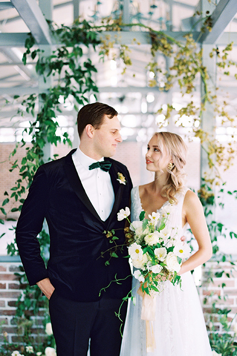  bride in a formfitting gown with long cathedral veil and the groom in a black velvet tuxedo 