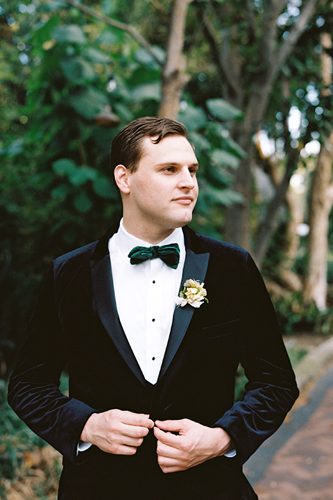  bride in a formfitting gown with long cathedral veil and the groom in a black velvet tuxedo 