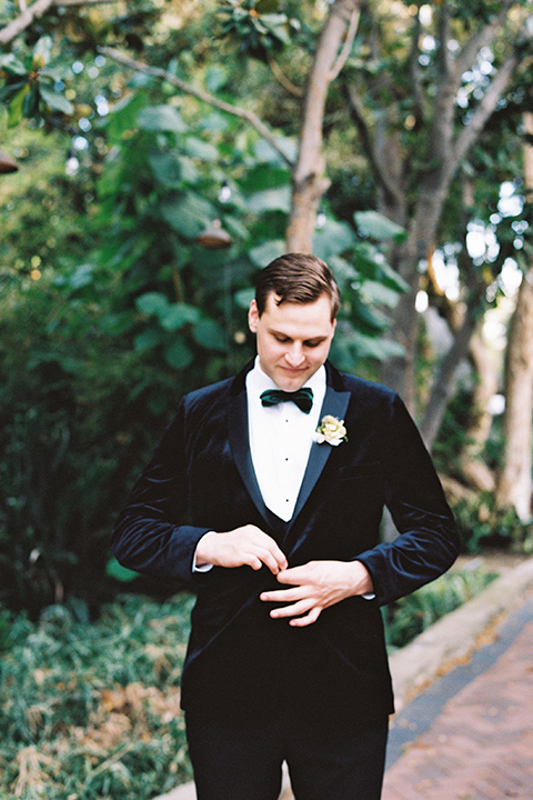  bride in a formfitting gown with long cathedral veil and the groom in a black velvet tuxedo