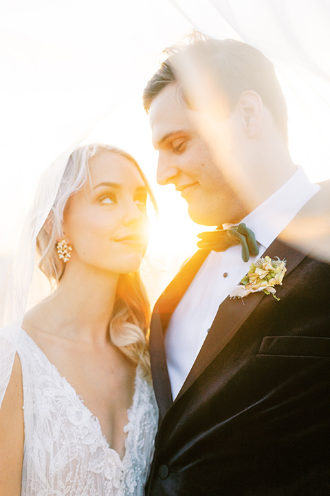  bride in a formfitting gown with long cathedral veil and the groom in a black velvet tuxedo 