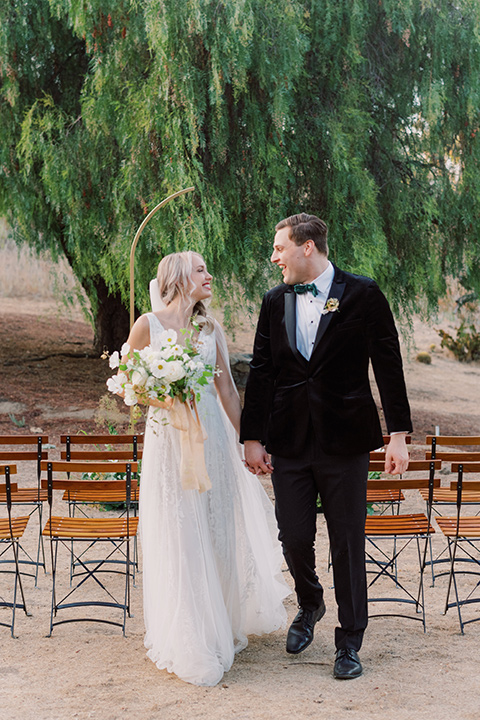  bride in a formfitting gown with long cathedral veil and the groom in a black velvet tuxedo 