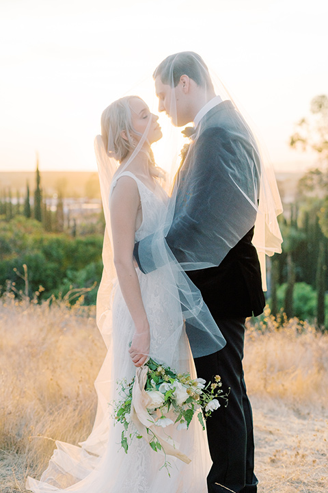  bride in a formfitting gown with long cathedral veil and the groom in a black velvet tuxedo