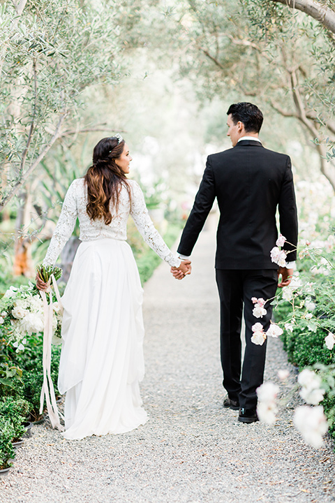  bride in a European inspired gown with lace details, a high neckline, and long sleeves and the groom in a black tuxedo and a black bow tie 