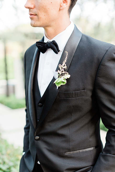 the groom in a black tuxedo and a black bow tie 