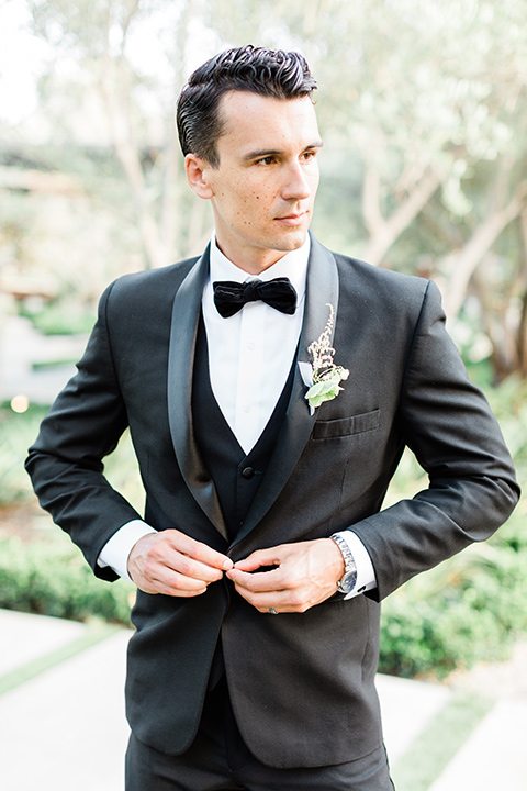  the groom in a black tuxedo with a black bow tie 